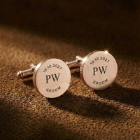 Round cufflinks with engraved text on a brown textured background